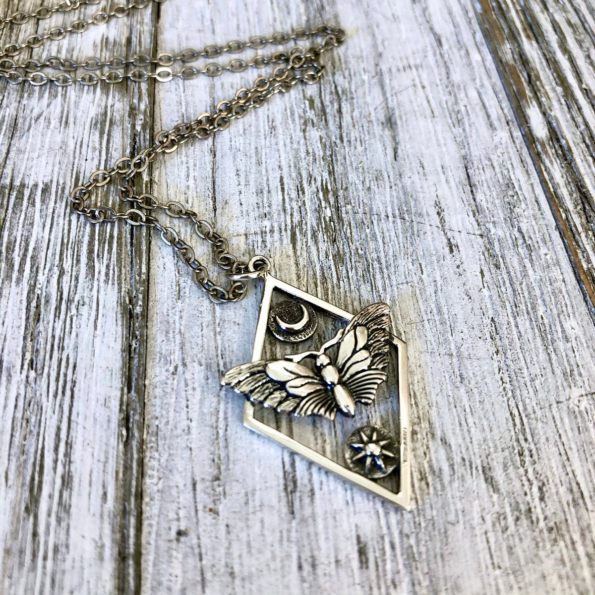 Sterling silver geometric moth necklace with sun and moon charms from FOXLARK Tiny Talisman Collection, 32x21mm.