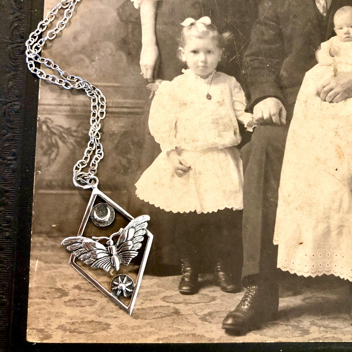 Sterling silver geometric moth necklace with sun and moon charms from FOXLARK Tiny Talisman Collection, 32x21mm.