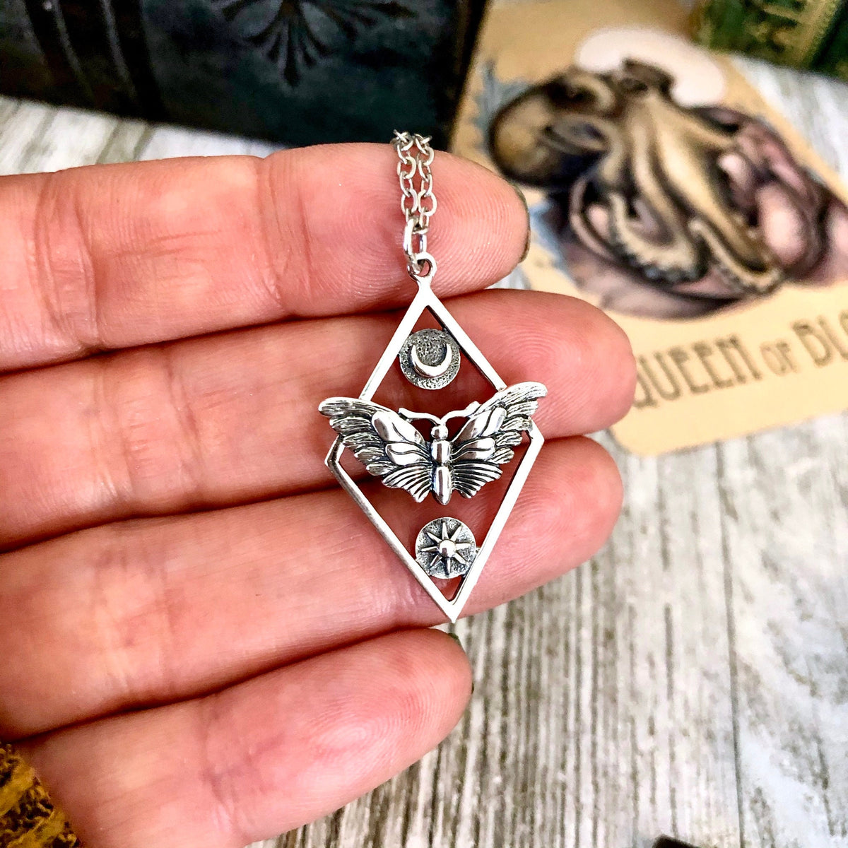 Sterling silver geometric moth necklace from FOXLARK Tiny Talisman Collection featuring sun and moon design, 32x21mm.