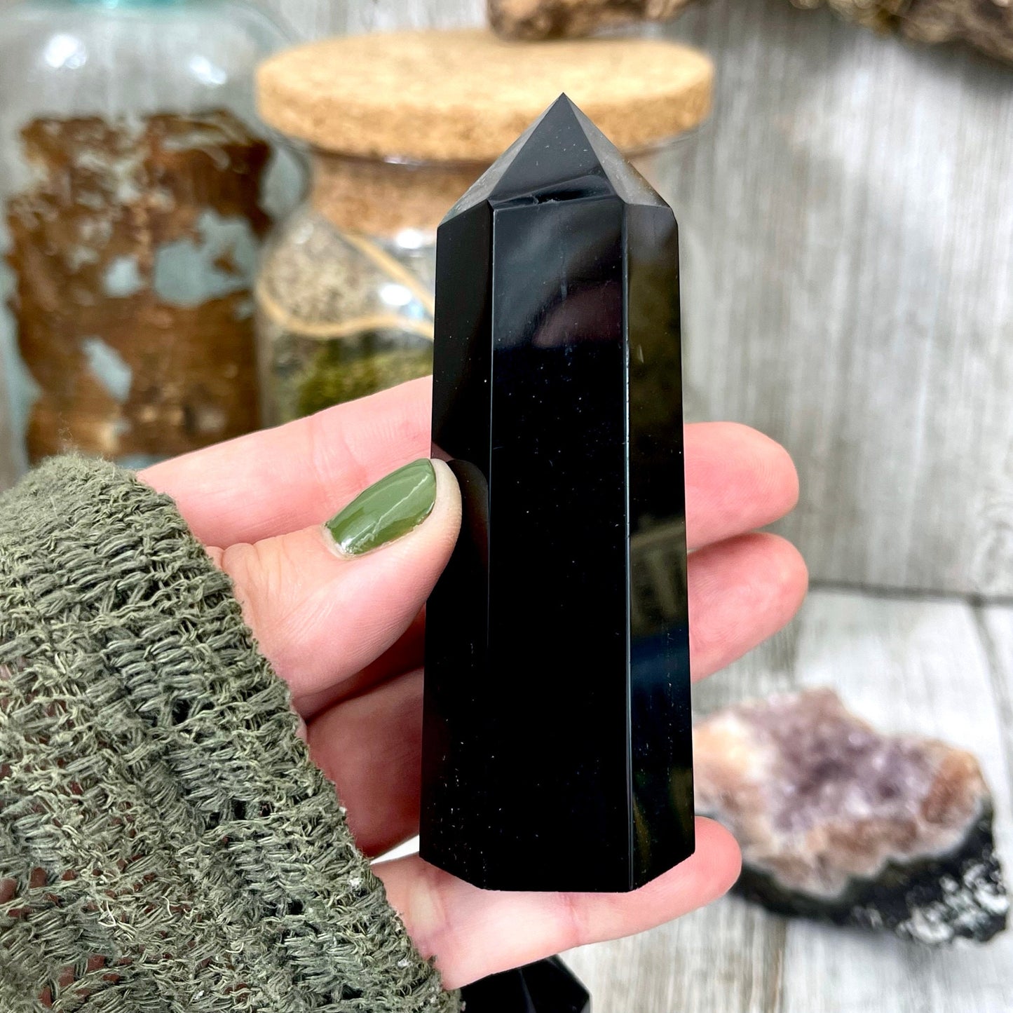 Self-standing black obsidian point crystal from FoxlarkCrystals, showcasing its polished, pointed shape and glossy black surface.