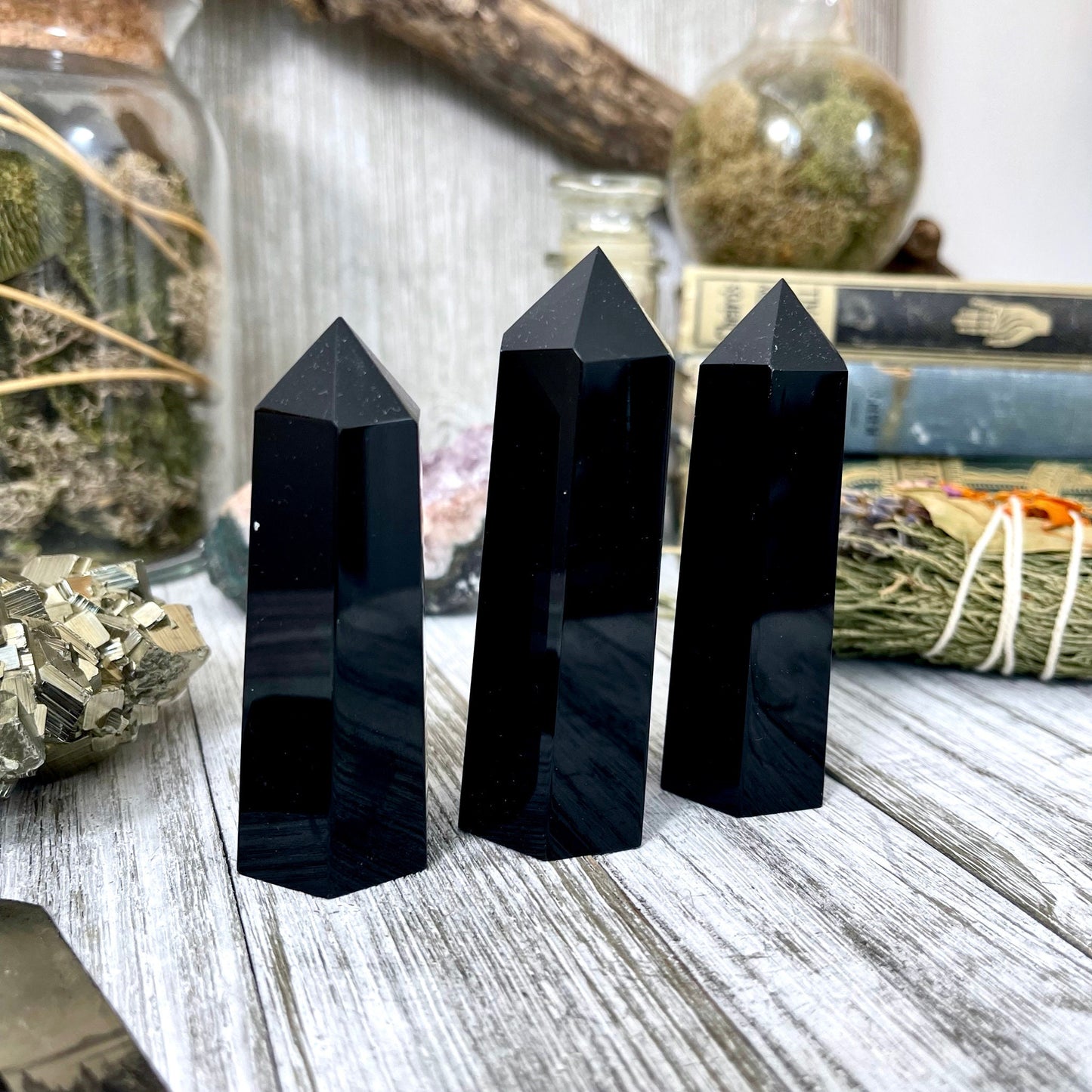 Self-standing black obsidian crystal point from FoxlarkCrystals, natural black volcanic stone with a pointed tip and polished surface.