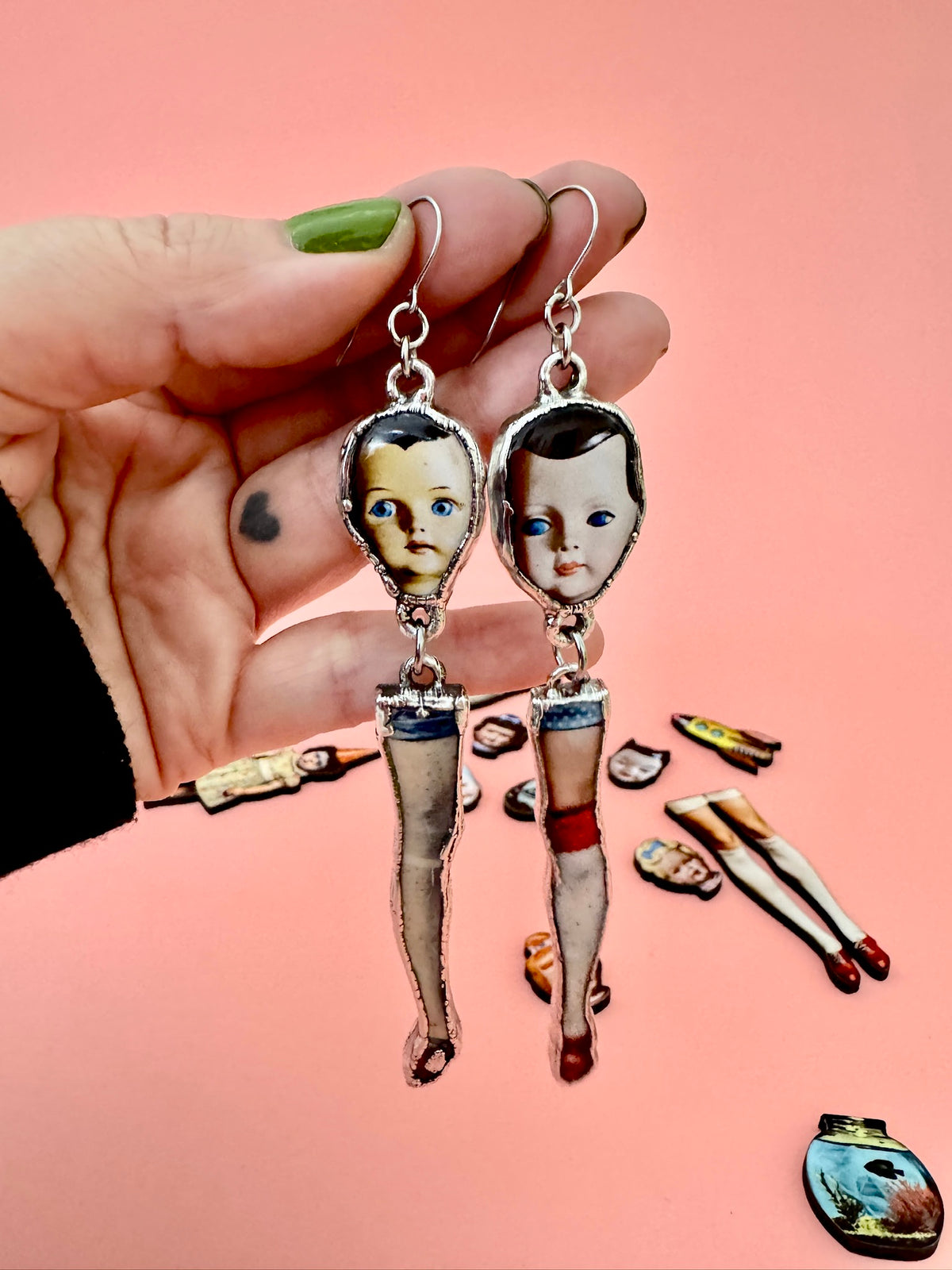 Silver mismatched doll head and leg earrings with long dangle design, statement jewelry from FOXLARK's Weirdlings Collection.